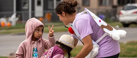 A women's soccer player works with two children in learning soccer.